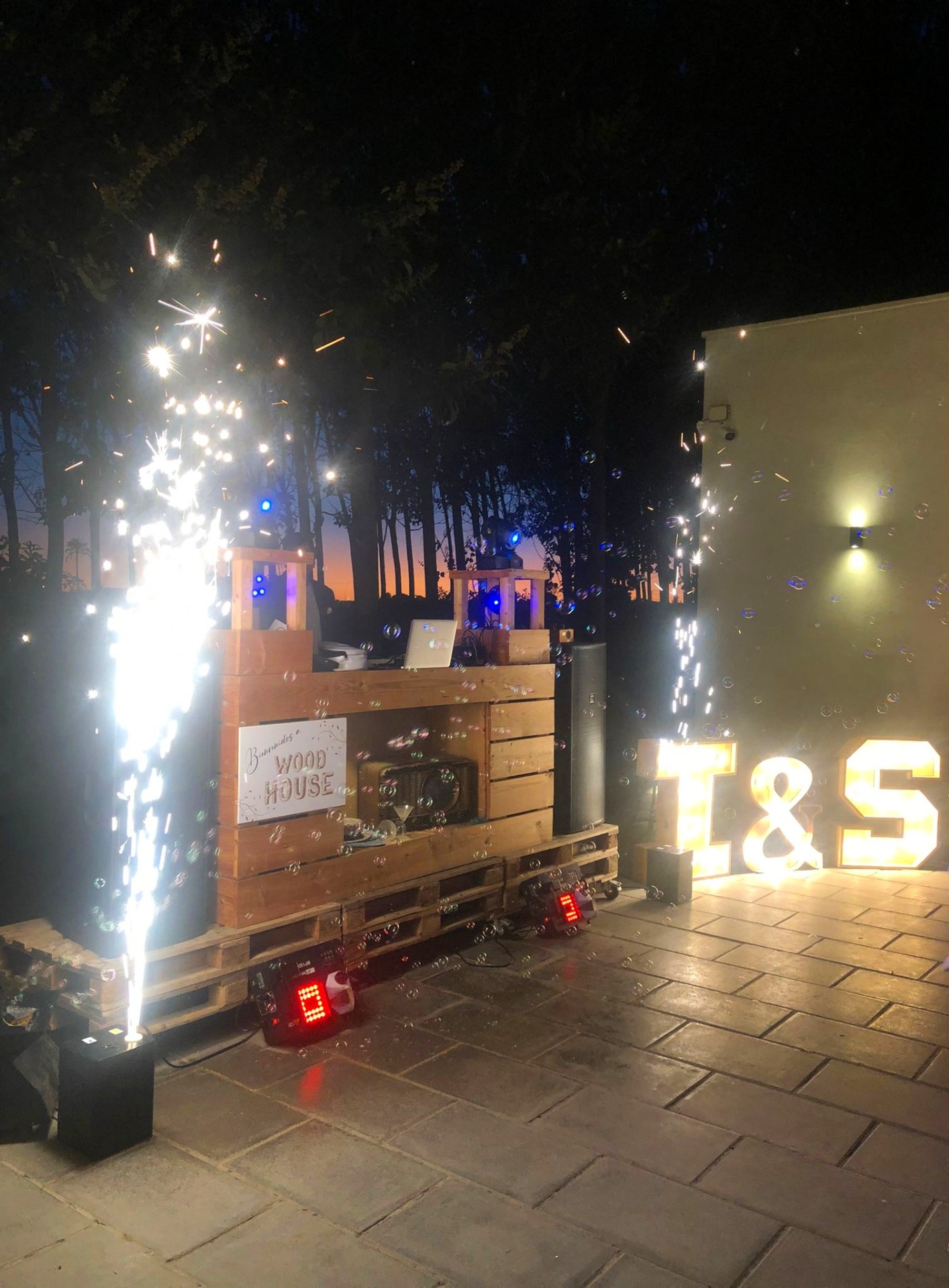 Decoración nocturna con letras luminosas y fuegos fríos en una boda